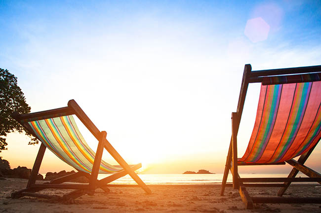 Betriebsferien Zwei Strandstühle am Meer mit Sonnenuntergang